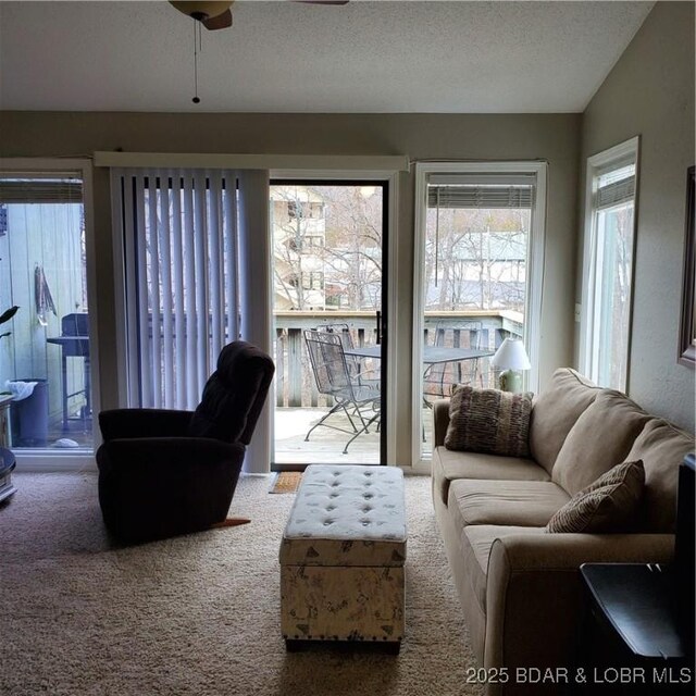 carpeted living room featuring ceiling fan, vaulted ceiling, and a textured ceiling