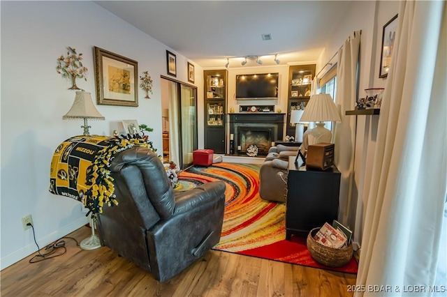 living room with visible vents, baseboards, a fireplace, rail lighting, and wood finished floors