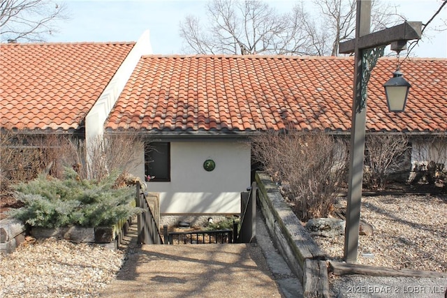 exterior space with stucco siding and a tiled roof