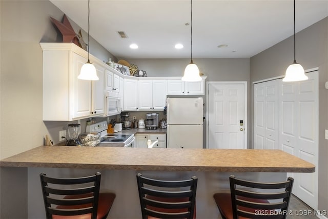 kitchen featuring white appliances, a kitchen bar, white cabinetry, kitchen peninsula, and pendant lighting