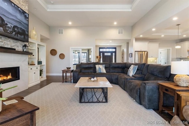 living room featuring hardwood / wood-style flooring, a tile fireplace, and a raised ceiling