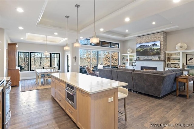 kitchen with pendant lighting, a center island, appliances with stainless steel finishes, and a tray ceiling