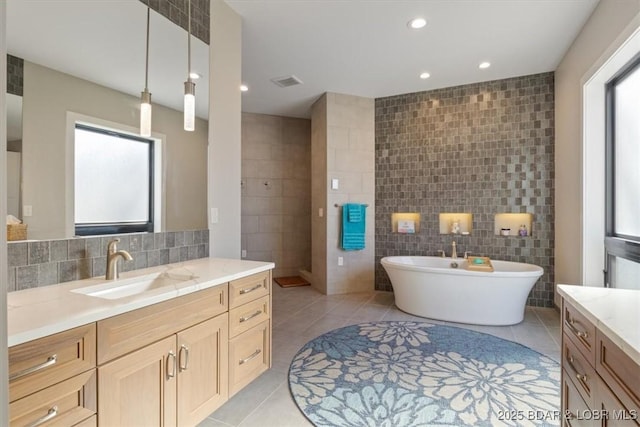 bathroom with tile walls, a bath, vanity, and tile patterned flooring