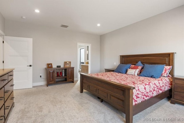 bedroom with connected bathroom and light carpet