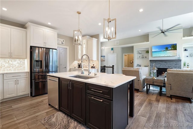 kitchen with tasteful backsplash, sink, white cabinets, pendant lighting, and stainless steel appliances