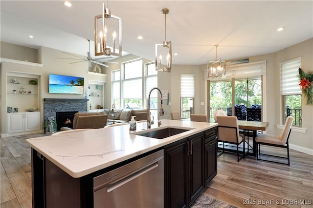 kitchen with pendant lighting, dishwasher, built in shelves, an island with sink, and sink