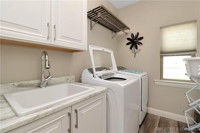 clothes washing area with washer and dryer, sink, dark hardwood / wood-style floors, and cabinets