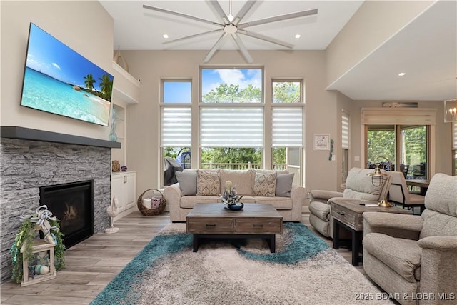 living room with light hardwood / wood-style floors, a notable chandelier, and a stone fireplace