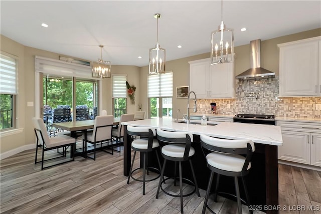 kitchen featuring sink, white cabinetry, backsplash, and wall chimney exhaust hood