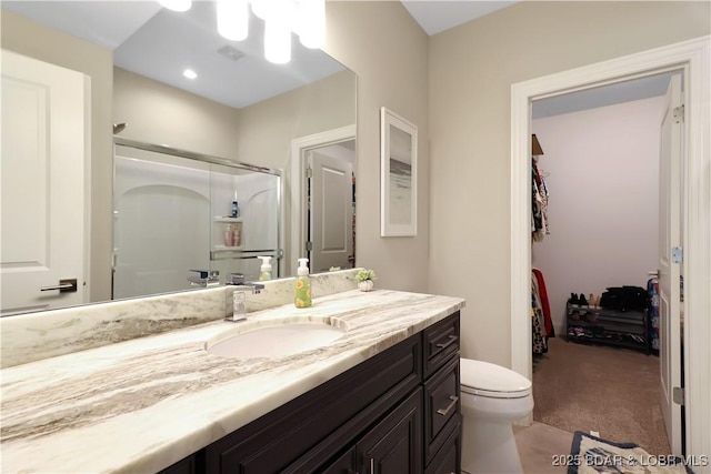 bathroom with a shower with shower door, toilet, and vanity