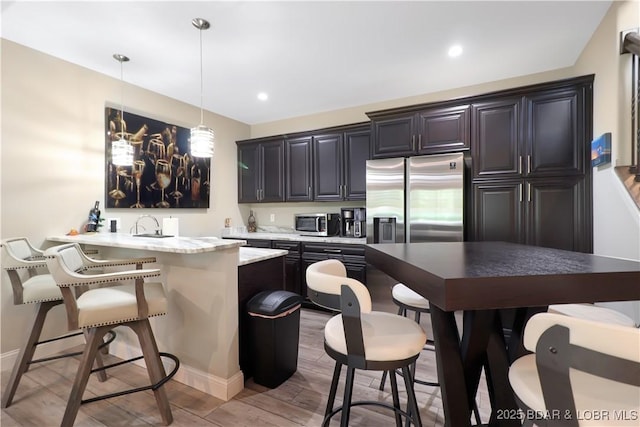 kitchen featuring a kitchen island, decorative light fixtures, stainless steel appliances, kitchen peninsula, and a breakfast bar