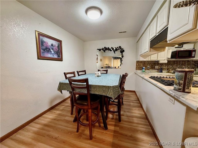 dining space featuring light hardwood / wood-style floors and a textured ceiling