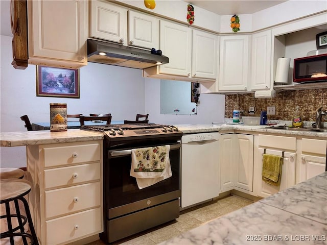 kitchen with kitchen peninsula, gas range, white dishwasher, sink, and a breakfast bar