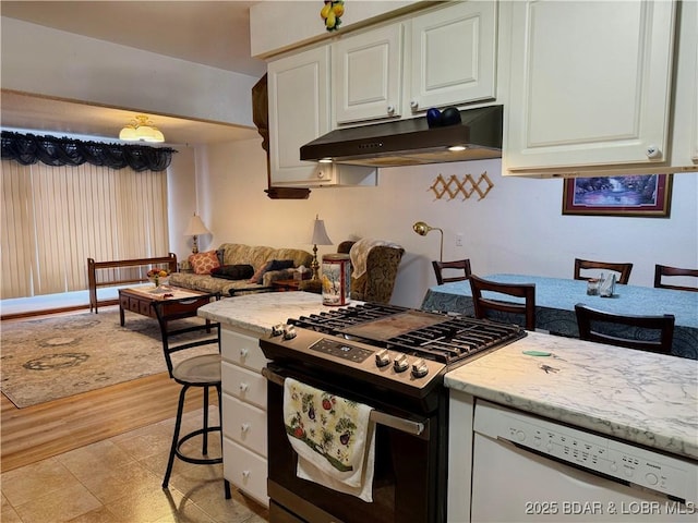 kitchen with gas range, white cabinetry, white dishwasher, and a breakfast bar area