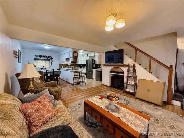 living room featuring a textured ceiling, sink, and light hardwood / wood-style flooring