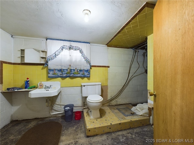 bathroom featuring sink, toilet, and concrete flooring