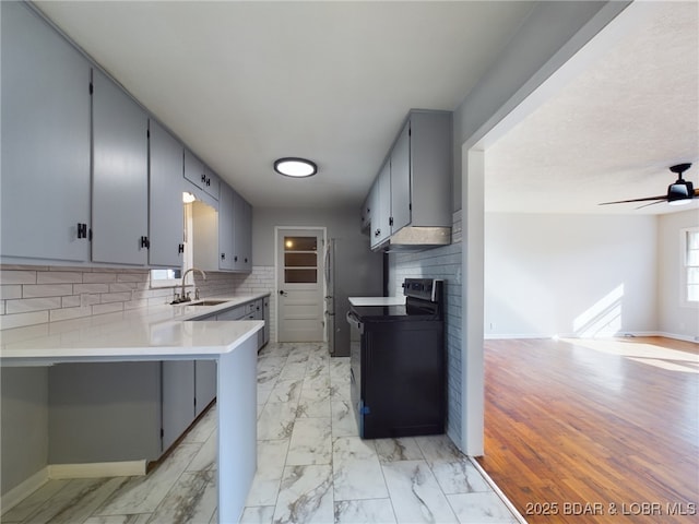 kitchen featuring tasteful backsplash, sink, kitchen peninsula, ceiling fan, and electric range oven