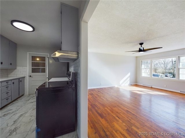 kitchen with washer / dryer, stove, gray cabinetry, decorative backsplash, and ceiling fan