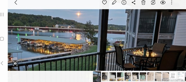 balcony at dusk featuring a water view