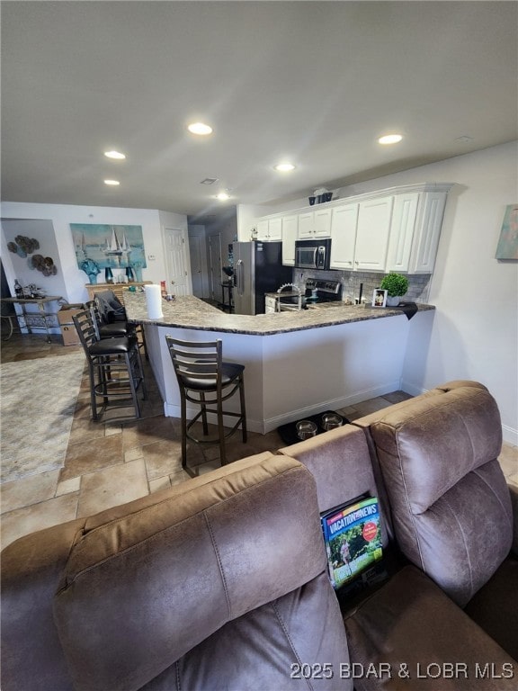 kitchen featuring stainless steel appliances, white cabinetry, a breakfast bar area, and kitchen peninsula