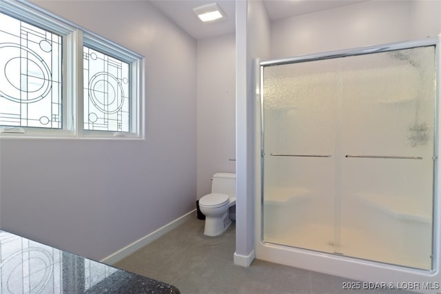 bathroom featuring a shower with shower door and toilet