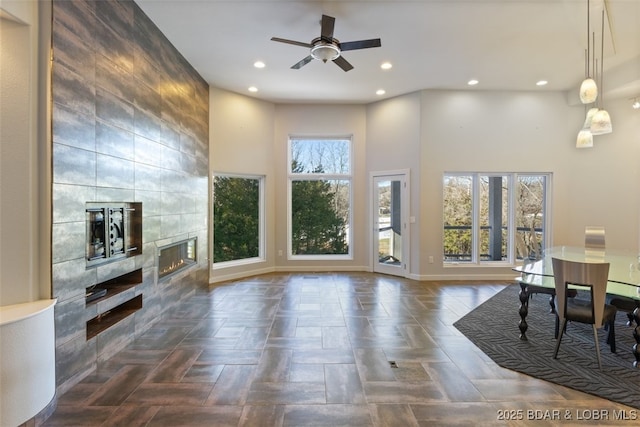 living room with a tiled fireplace and ceiling fan