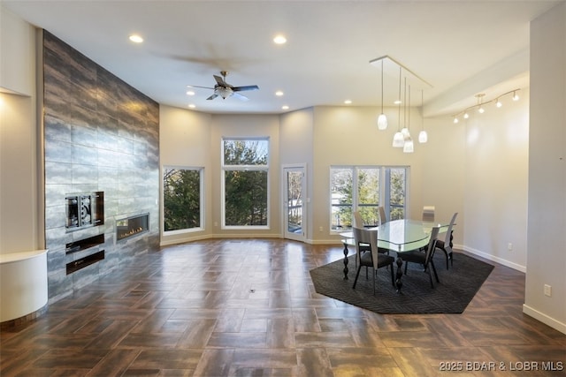 dining room with a tile fireplace, dark parquet floors, and ceiling fan