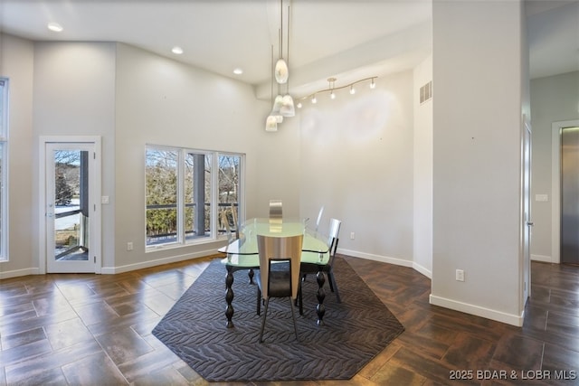 dining area with a high ceiling and dark parquet flooring