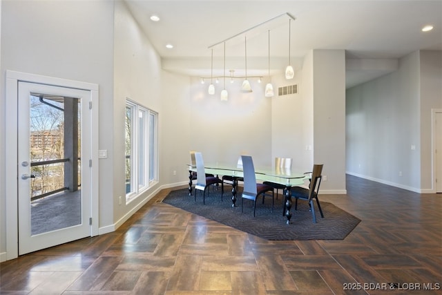 dining room with a towering ceiling and dark parquet floors