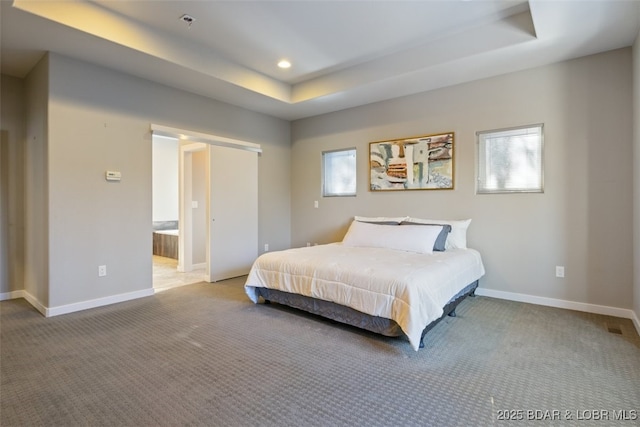 carpeted bedroom with connected bathroom and a tray ceiling