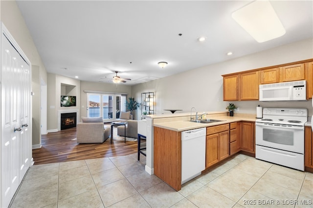 kitchen with sink, light tile patterned floors, white appliances, and kitchen peninsula