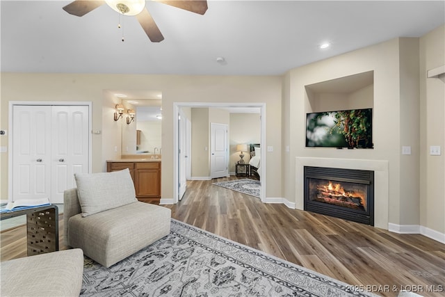 living room featuring ceiling fan, wood-type flooring, and sink