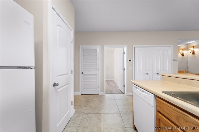 kitchen with sink, light tile patterned floors, and white dishwasher