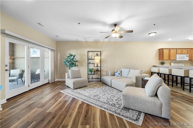 living room featuring ceiling fan and dark hardwood / wood-style flooring