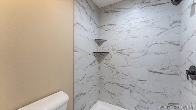 bathroom featuring toilet and a tile shower