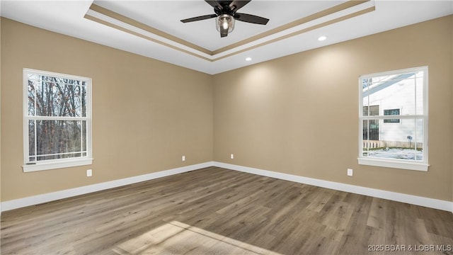 unfurnished room with ceiling fan, wood-type flooring, and a raised ceiling