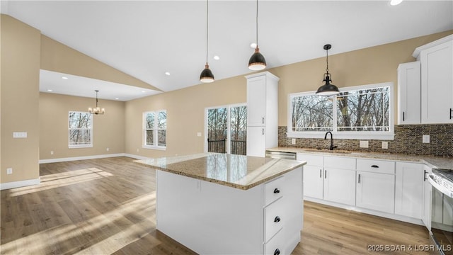 kitchen featuring white cabinets, a kitchen island, light stone countertops, and sink