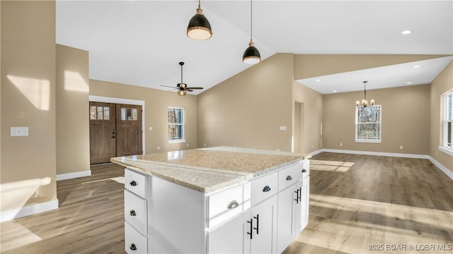 kitchen featuring light stone countertops, white cabinets, lofted ceiling, and a kitchen island