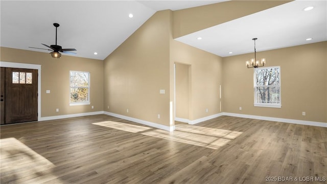 interior space featuring ceiling fan with notable chandelier, light hardwood / wood-style flooring, and high vaulted ceiling