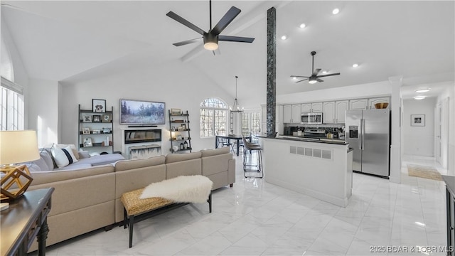 living room with ceiling fan with notable chandelier, beam ceiling, and high vaulted ceiling