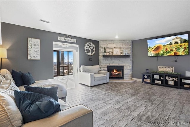 living room with hardwood / wood-style flooring and a stone fireplace