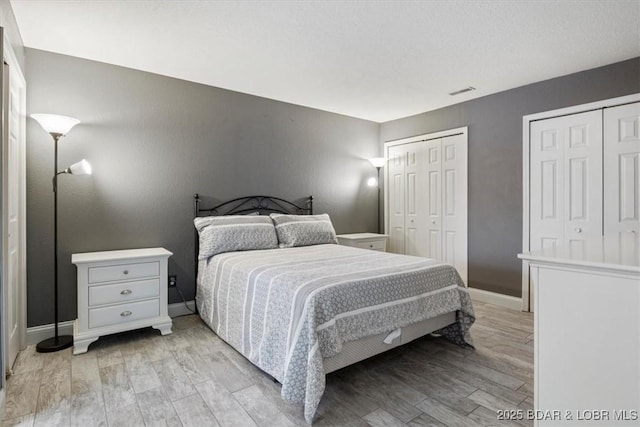 bedroom with multiple closets and light wood-type flooring