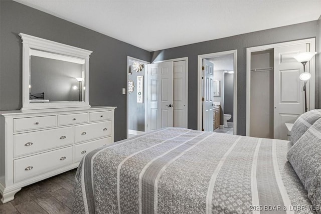 bedroom featuring two closets, dark hardwood / wood-style floors, and ensuite bath