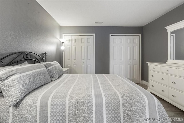 bedroom featuring hardwood / wood-style floors and two closets