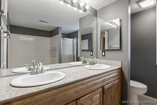 bathroom with a textured ceiling, tile patterned floors, vanity, toilet, and a shower with shower door