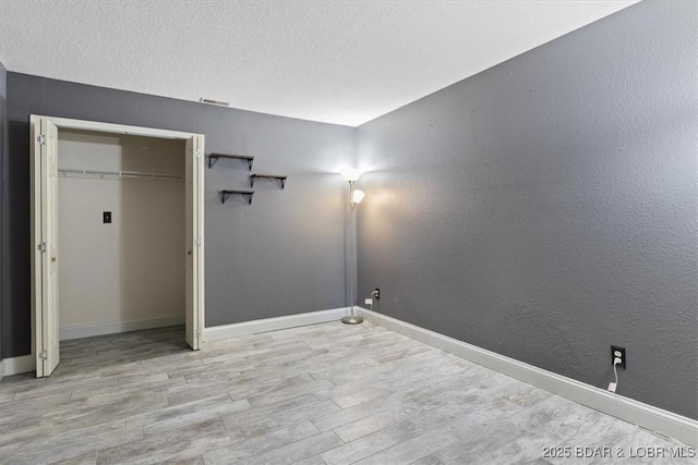 unfurnished bedroom featuring a closet, light hardwood / wood-style flooring, and a textured ceiling