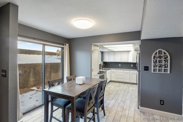 dining area featuring sink, light hardwood / wood-style floors, and a textured ceiling