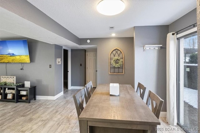 dining room featuring a textured ceiling and light wood-type flooring