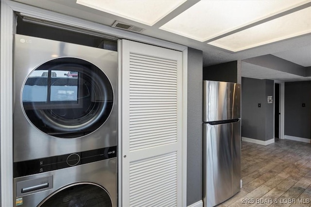 laundry area with hardwood / wood-style flooring and stacked washer / dryer