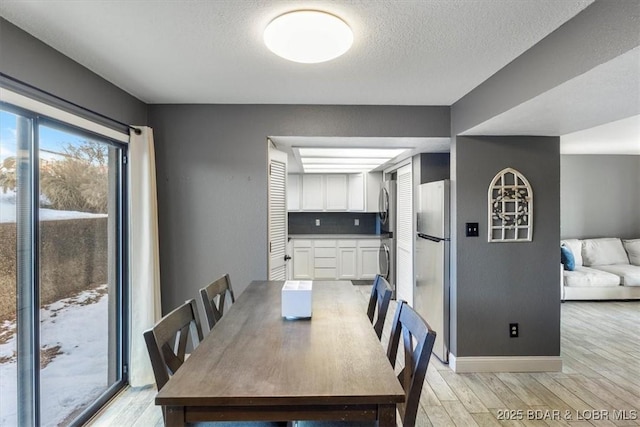 dining area featuring light wood-type flooring and a textured ceiling